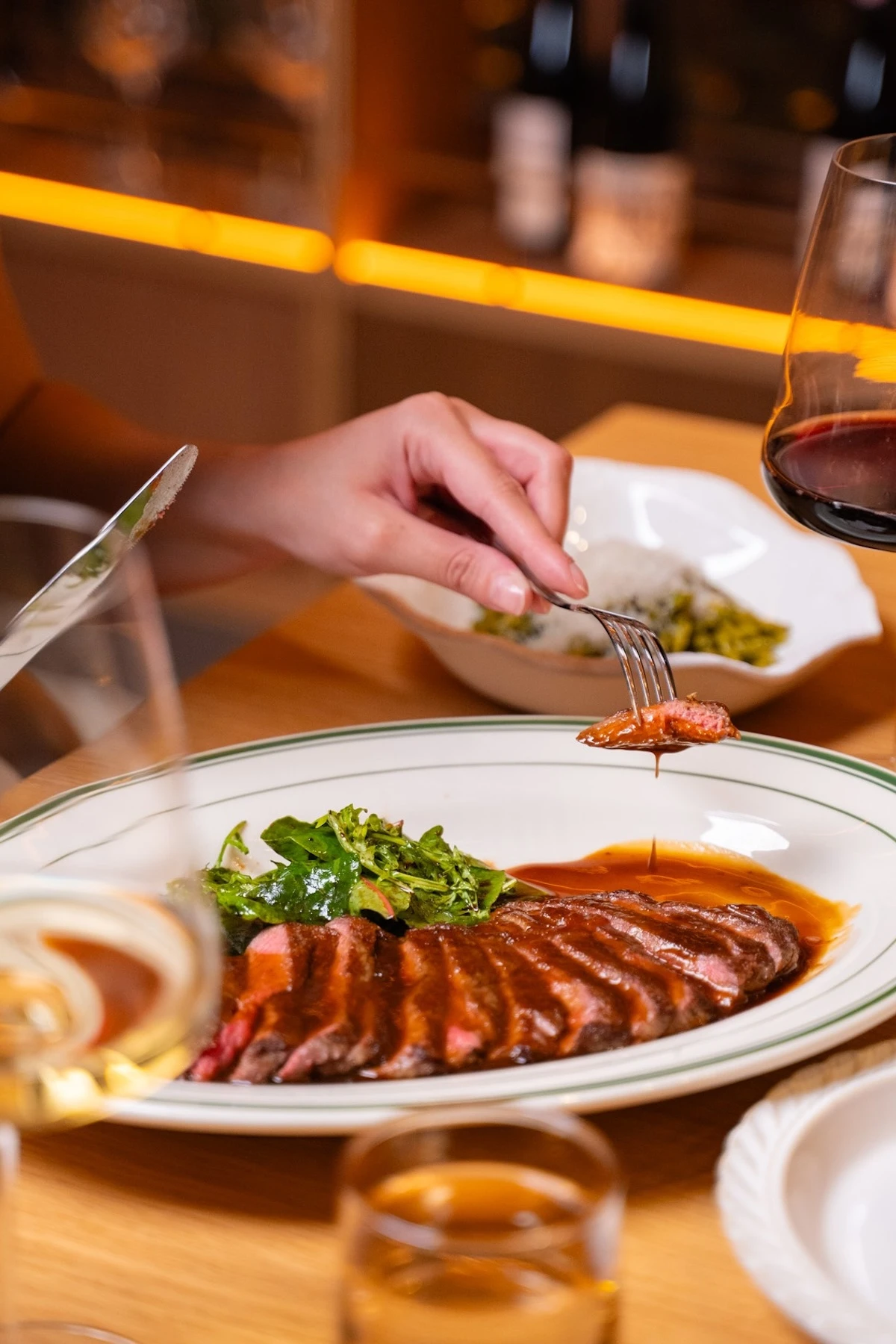 A succulent steak served with fresh greens and paired with red wine. An elegant setup for a refined dining experience. at 1010 Wine Bar restaurant