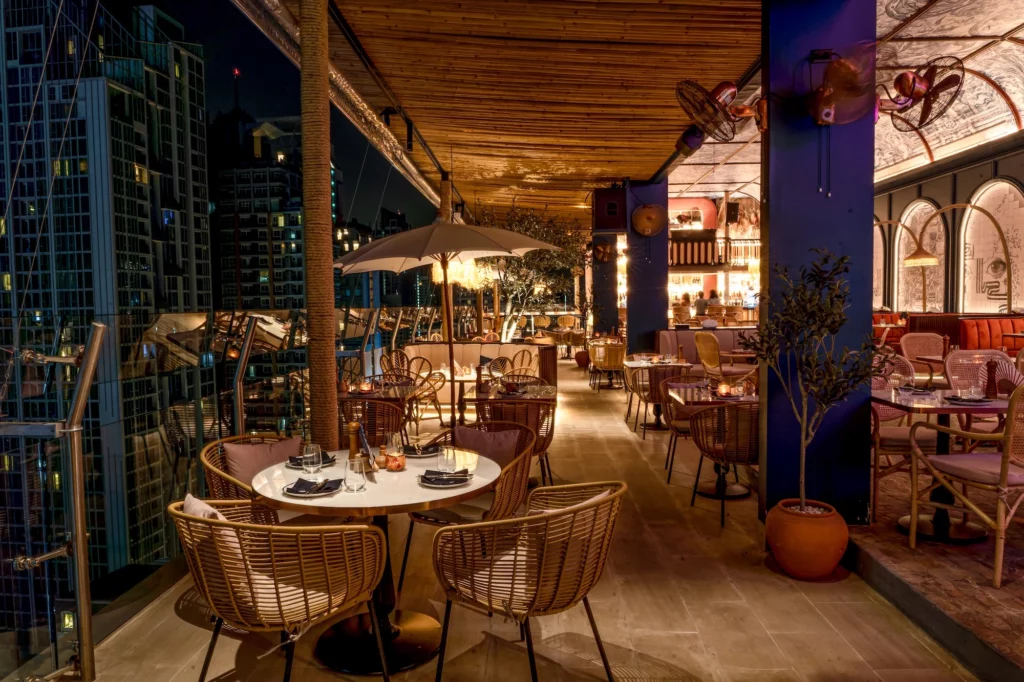 The outdoor terrace of Pastel Rooftop Bar and Restaurant in Bangkok offers a perfect romantic setting at night, with soft lighting, and stunning city views, ideal for a dinner date with cocktails