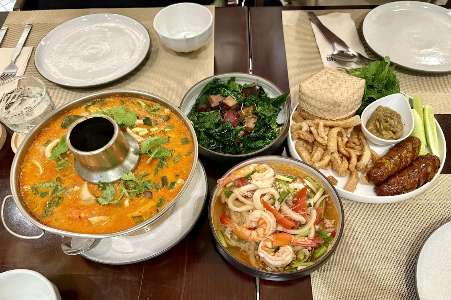 A spread of traditional Thai dishes, including spicy soup, shrimp salad, and grilled sausage. Perfect for a flavorful and authentic Thai meal at Napha restaurant